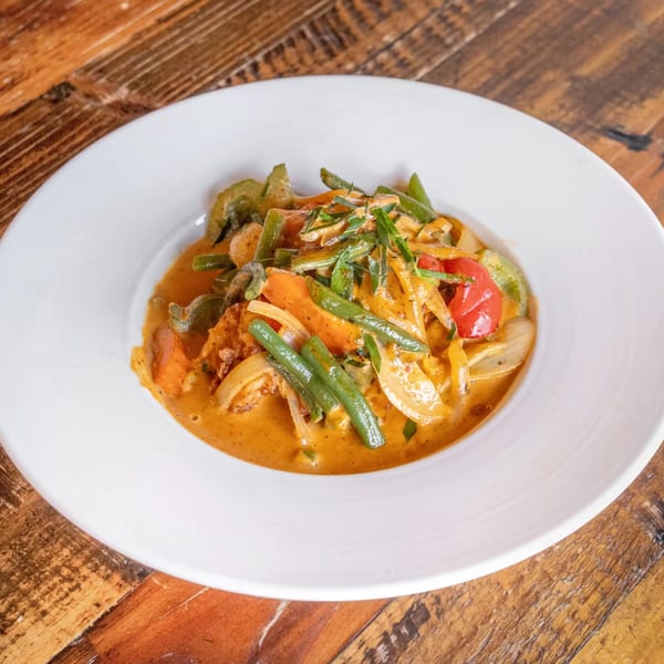 Siwa Thai Restaurant's red curry with green beans, bell peppers, and onions in a white bowl.