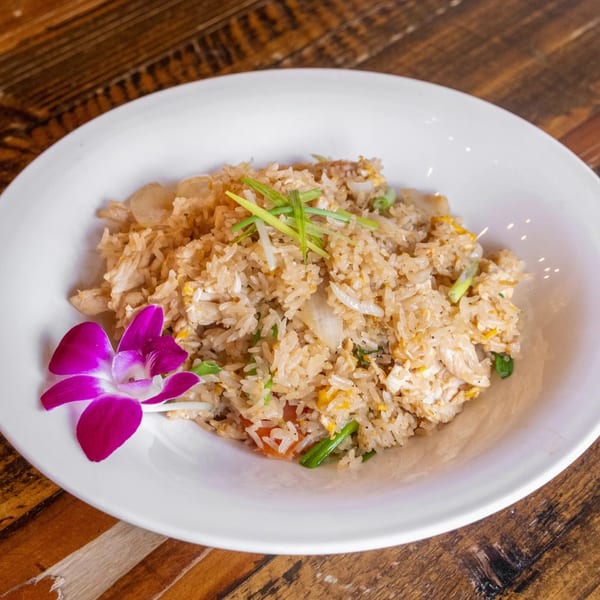 Siwa Thai Restaurant's fried rice with chicken, onions, and scallions, garnished with a purple orchid.